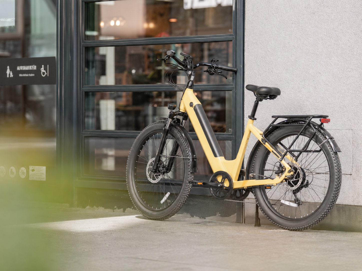 Gele stads-e-bike geparkeerd voor een winkelpui