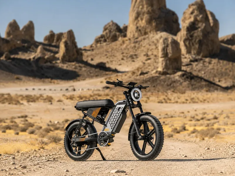 Bicicleta elétrica de pneu largo numa estrada de terra no deserto, com formações rochosas ao fundo